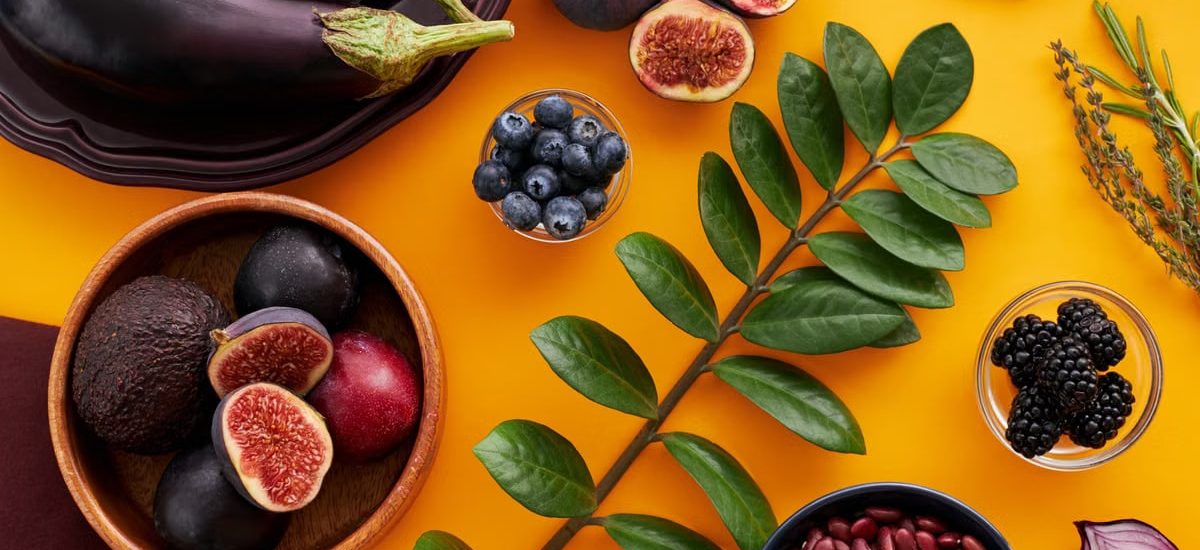 Top view of colorful fruits and vegetables on a vibrant orange background, perfect for healthy lifestyle concepts.