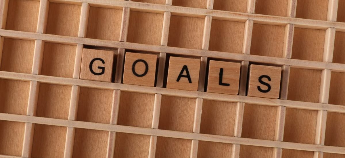 Wooden alphabet tiles spelling 'GOALS' on a grid background, symbolizing aspirations.